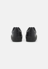 Sneakers neri con una toma in pelle liscia, colletto imbottito e suola in gomma testurizzata. Design con punta rotonda e perforazioni per la traspirabilità.