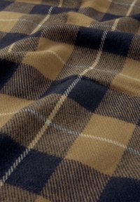 Tissu à texture douce avec un motif à carreaux marron et bleu foncé, comprenant des lignes diagonales et verticales ainsi que des plis subtils.