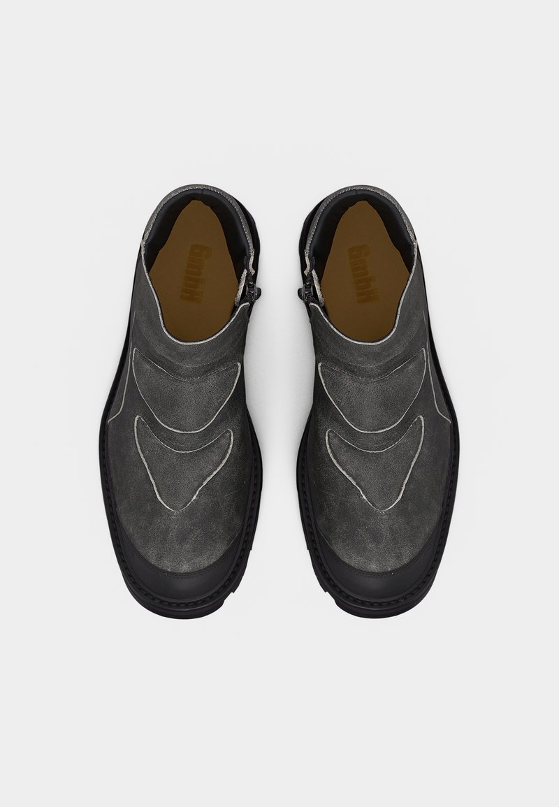 Pair of dark gray suede slip-on shoes with black soles and subtle stitched design, shown from a top-down view on a white background.