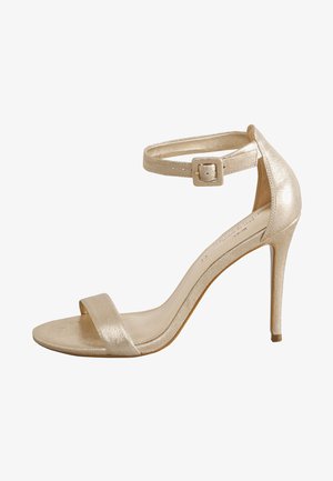 Gouden metalen sandaal met hoge hak, enkelbandje, open teen en een smalle stilettohak. Soepele textuur met minimalistisch design.