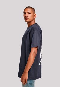 Navy blue cotton t-shirt with short sleeves, crew neck, and large white graphic print on the back. Simple, relaxed fit design.