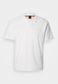 Polo blanc à manches courtes avec col, trois boutons et logo discret "BOSS" brodé sur la poitrine gauche.