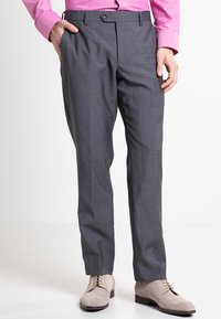 Grå dressbukser med et subtilt ternet mønster, der har en knaplukning, to sidelommer og en skræddersyet pasform. Båret med beige sko.