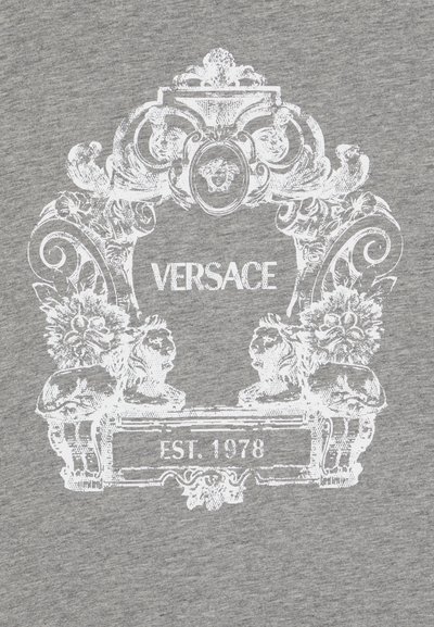 Camiseta gris con estampado blanco ornamentado que incluye "VERSACE" y "EST. 1978", adornada con figuras y elementos florales en un estilo barroco.