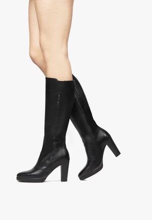 Bottes en cuir noir jusqu'au genou avec un talon haut épais, une fermeture éclair sur le côté et des panneaux texturés en accent. Fini lisse, silhouette élégante.