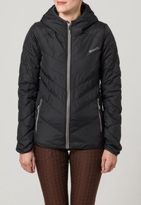 Doudoune noire avec piqûres en chevrons, fermeture éclair à l'avant et capuche. Comprend deux poches latérales et des accents gris, portée avec un legging à motifs.