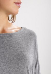 Grauer Strickpullover mit weitem Ausschnitt und weicher Textur, verfügt über einen entspannten Schnitt und sichtbare Nähte.
