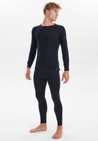 Black long-sleeve thermal top and fitted leggings made of soft, stretchy fabric. Features ribbed cuffs and a crew neckline.