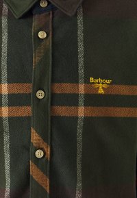 Camicia in flanella verde con motivo a quadri; presenta strisce marroni e bianche, due bottoni e un logo ricamato "Barbour" giallo.