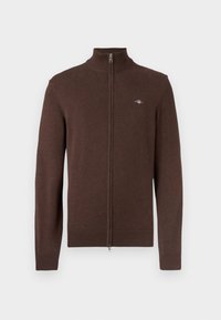 Brūns džemperis ar rāvējslēdzēju un augstu apkakli, ar ribainām aprocēm un apakšmalu. Mīksta tekstūra ar nelielu logotipu kreisajā krūtīs.