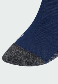 Calcetín azul marino con un acabado texturizado, que presenta una puntera y un talón con un patrón gris oscuro. Su construcción sin costuras mejora la comodidad y la durabilidad.
