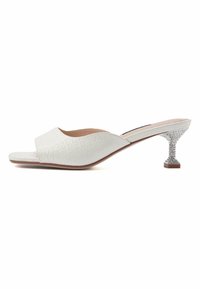 Mule en cuir blanc à bout ouvert avec une finition texturée, dotée d'un talon bloc argenté scintillant et d'une courbe subtile dans le design.