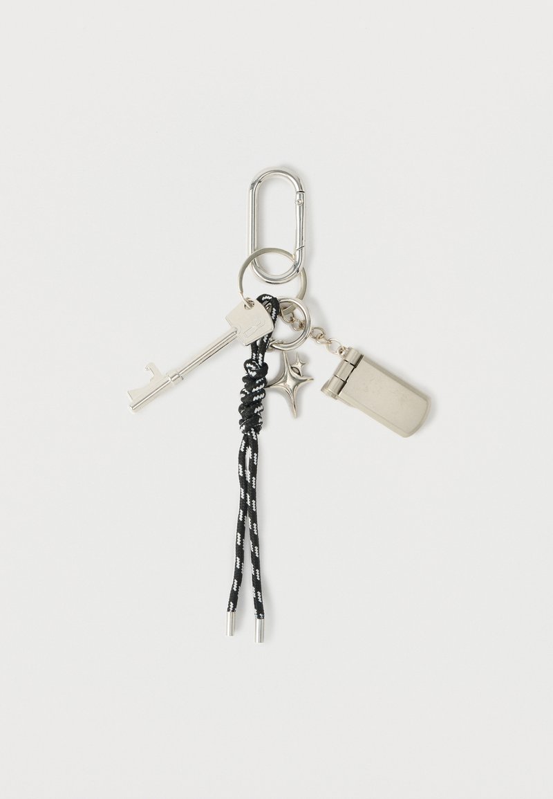 Porte-clés avec une clé en métal argenté, un briquet argenté, un pendentif en forme d'étoile et une cordelette tressée noire et blanche, avec deux embouts en argent.