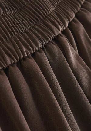 Brown textured fabric with pleated design and gathered waist. The material appears soft and stretchy, showcasing intricate stitching details.