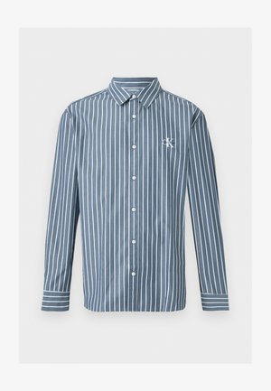 Camisa azul de manga larga con botones, con rayas blancas verticales y un pequeño logo blanco "CK" en el pecho izquierdo.