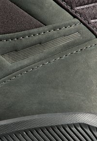 Scarpa scura in suede verde con tessuto nero testurizzato, caratterizzata da linee orizzontali e una suola in gomma con battistrada a motivo.