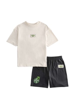Camiseta beige de manga corta y pantalones cortos negros con cintura elástica y parches verdes con temática de Minecraft "Overworld Club" en la parte delantera.