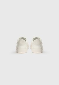 Sneakers bianchi in pelle con finitura liscia, caratterizzati da un design semplice, collo imbottito e un accento testurizzato sul tallone. Suola in gomma piatta.
