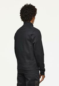 Hanorac negru cu guler înalt, cu mâneci lungi, având țesătură texturată, manșete elastice și o siluetă ajustată. Design minimalist, fără decoruri.