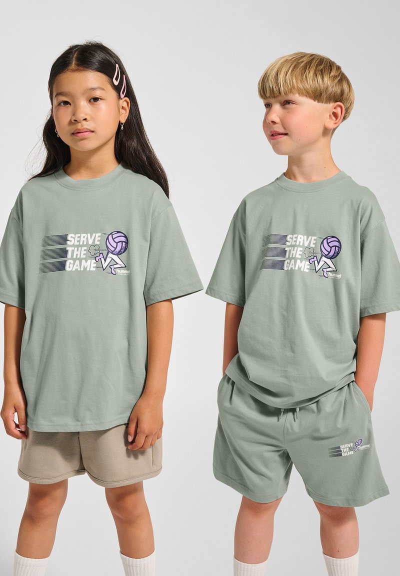 Mintgröna bomulls-t-shirts med grafiska tryck som säger "SERVE THE GAME", kombinerat med beige shorts. Enkelt mönster, avslappnad passform.