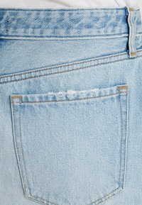 Jeans in denim azzurro chiaro con un classico design a cinque tasche e una tasca posteriore leggermente scucita con dettagli di cucitura.