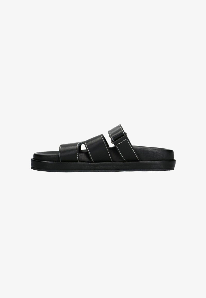 Sandales en cuir noir avec deux bandes horizontales, une ouverture pour le gros orteil et une semelle plate ; présente des coutures blanches contrastantes.