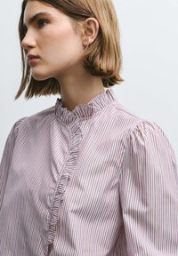 Striped blouse in pastel tones, featuring a ruffled high neckline and puffed sleeves; smooth fabric with fine vertical stripes.