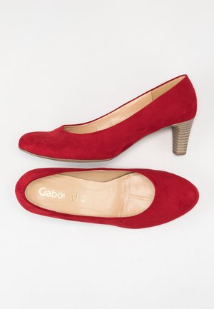Czerwone zamszowe szpilki z okrągłym noskiem i teksturowanym, średniej wysokości, warstwowym obcasem. Wnętrze wykończone gładką, beżową podszewką, z napisem "Gabor".