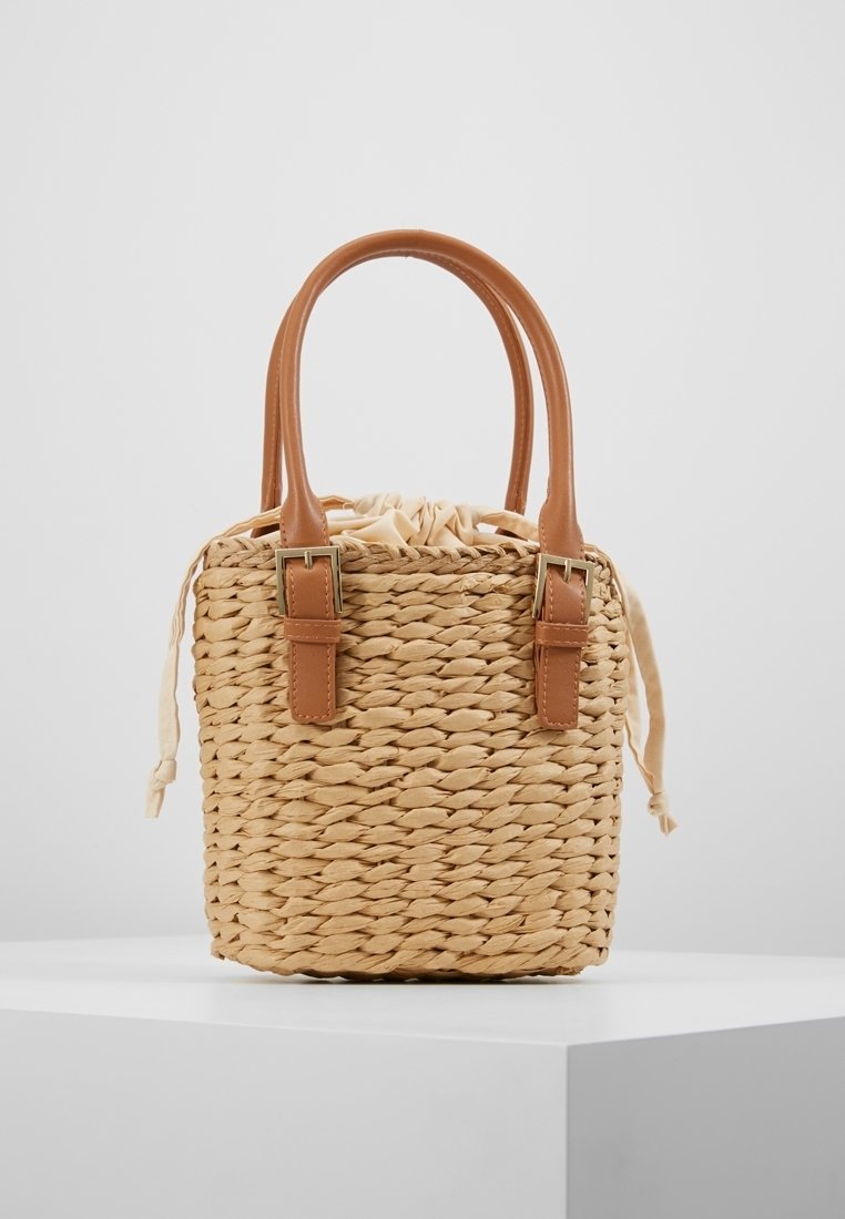 Borsa a tracolla in paglia intrecciata con manici in pelle sintetica marrone e dettagli in fibbia, dotata di chiusura a coulisse e superficie testurizzata.