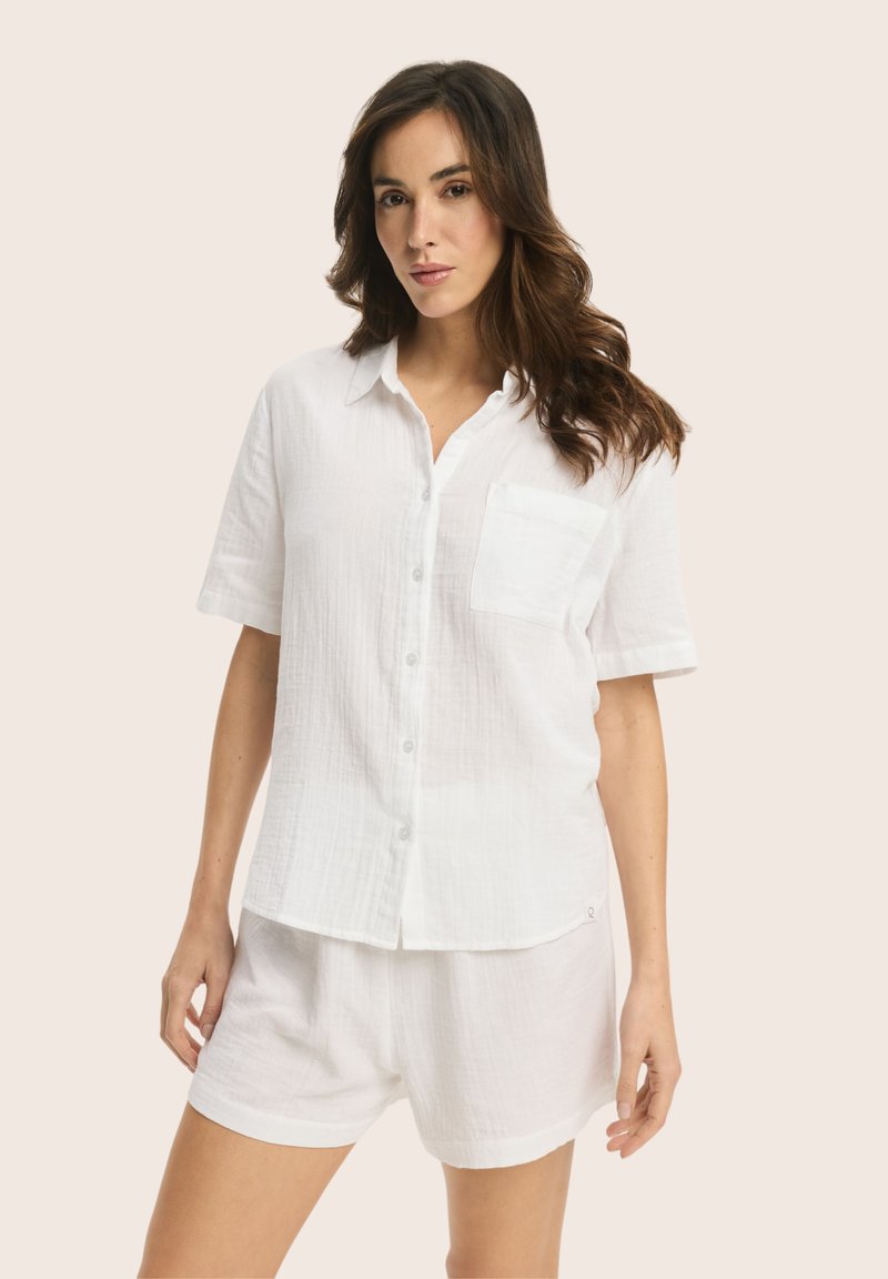 White short-sleeve button-up shirt with a front pocket, made of lightweight fabric, paired with matching white shorts. Smooth texture.