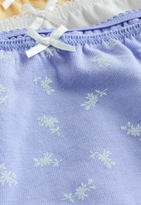 Lichtpaarse stof met kleine witte bloempatronen, voorzien van een gegatherde elastische band in de taille en een witte satijnen strikaccent.