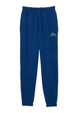 Los pantalones deportivos de algodón azules cuentan con una cintura elástica, bolsillos laterales y un pequeño logotipo de cocodrilo verde en la cadera izquierda.