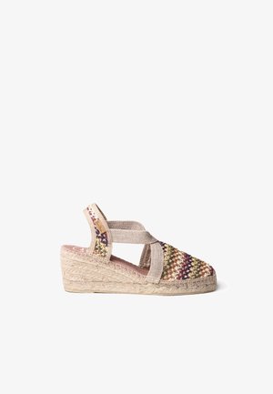 Sandalia espadrille de cuña con parte superior de tela tejida multicolor, correa beige en el tobillo y suela trenzada de yute sobre fondo blanco.