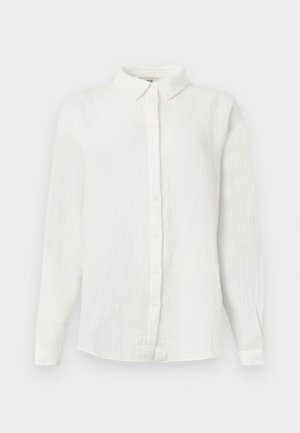 Λευκό πουκάμισο από ρυτιδωτό ύφασμα με μακριά μανίκια, μυτερό γιακά και κλείσιμο με κουμπιά στο μπροστινό μέρος, παρουσιάζεται σε απλό φόντο.