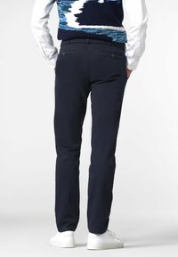 Navy chinos made of lightweight fabric, featuring a straight cut, two back pockets with buttons, and worn with white sneakers.