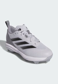 Zapatilla deportiva gris con parte superior de malla, acentos negros y puntas de goma en la suela. Presenta un sistema de cierre con cordones y una pestaña de tracción en el talón.