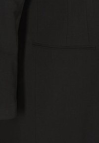 Blazer noir présentant une texture de tissu lisse, une silhouette structurée, des manches longues et une poche passepoilée simple sur la poitrine.