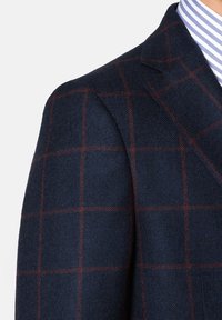 Marynarski, kraciasty żakiet z teksturowanej tkaniny, z czerwono-niebieskim wzorem w kratkę. Klapki w kształcie notcha i strukturalne detale na ramionach.