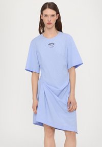 Blue striped dress with short sleeves, round neckline, asymmetrical hem, featuring a black logo print on the chest and soft textured fabric.