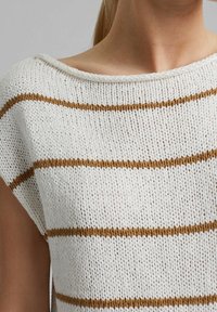 Raidallinen valkoinen neulepaita, jossa ruskeat vaakaraitaiset kuviot; siinä on leveä pääntie ja lyhyet hihat; tekstuuri on ilmava ja väljä.