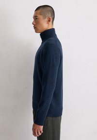 Navyfarbener Wollrollkragenpullover mit geripptem Kragen und Saum. Glatte Textur mit körperbetontem Design, ergänzt durch eine minimalistische Silhouette.