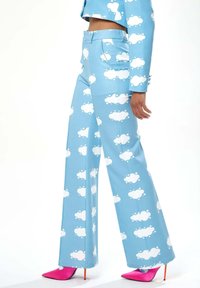 Blue wide-leg trousers with white cloud patterns and a smooth texture. Paired with bright pink pointed heels.