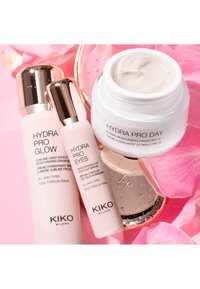 Tre KIKO Milano hudpleieprodukter på rosa kronblader: Hydra Pro Glow-krem, Hydra Pro Eyes-serum og åpen Hydra Pro Day-fuktighetskrem.