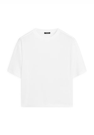 White cropped t-shirt made from soft cotton. Features a round neckline and short sleeves with a relaxed fit, minimalistic design.