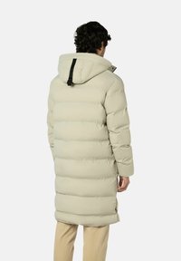 Opvulpak in lichtbeige, voorzien van doorgestikte panelen, een capuchon en een zwarte riemaccent op de achterkant. Het heeft een lang design en een ontspannen pasvorm.