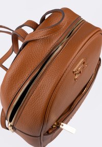 Zaino in pelle marrone con dettagli dorati, forma rotonda, doppia cerniera e logo in rilievo. Presenta una superficie testurizzata e spallacci regolabili.