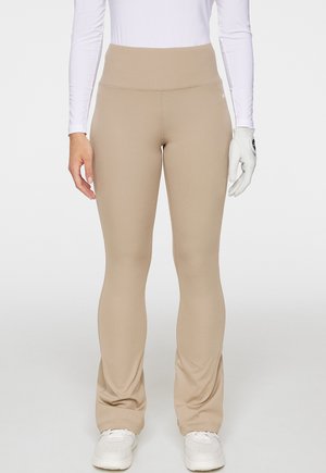 Beige högmidjade leggings tillverkade av elastiskt material, med en slät yta, kroppsnära design och diskreta sömdetaljer.