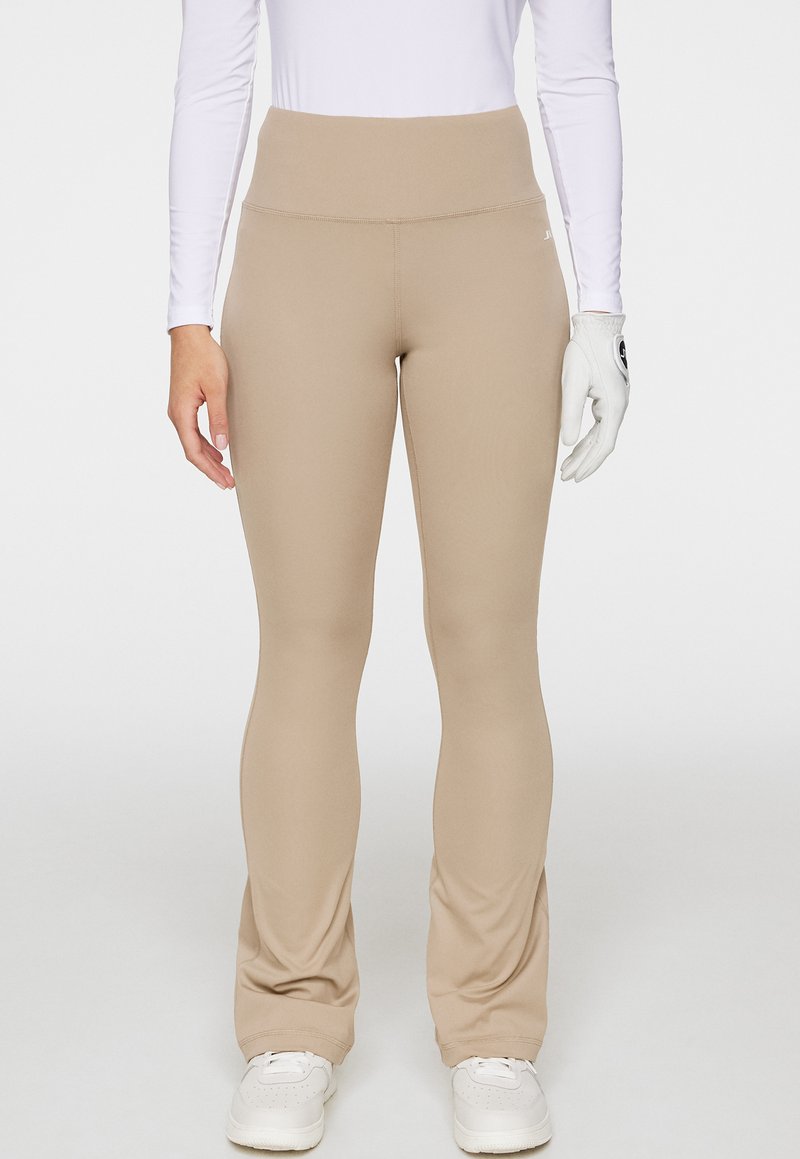 Leggings beiges taille haute en tissu extensible, avec une texture lisse, une coupe ajustée et de subtils détails de couture.