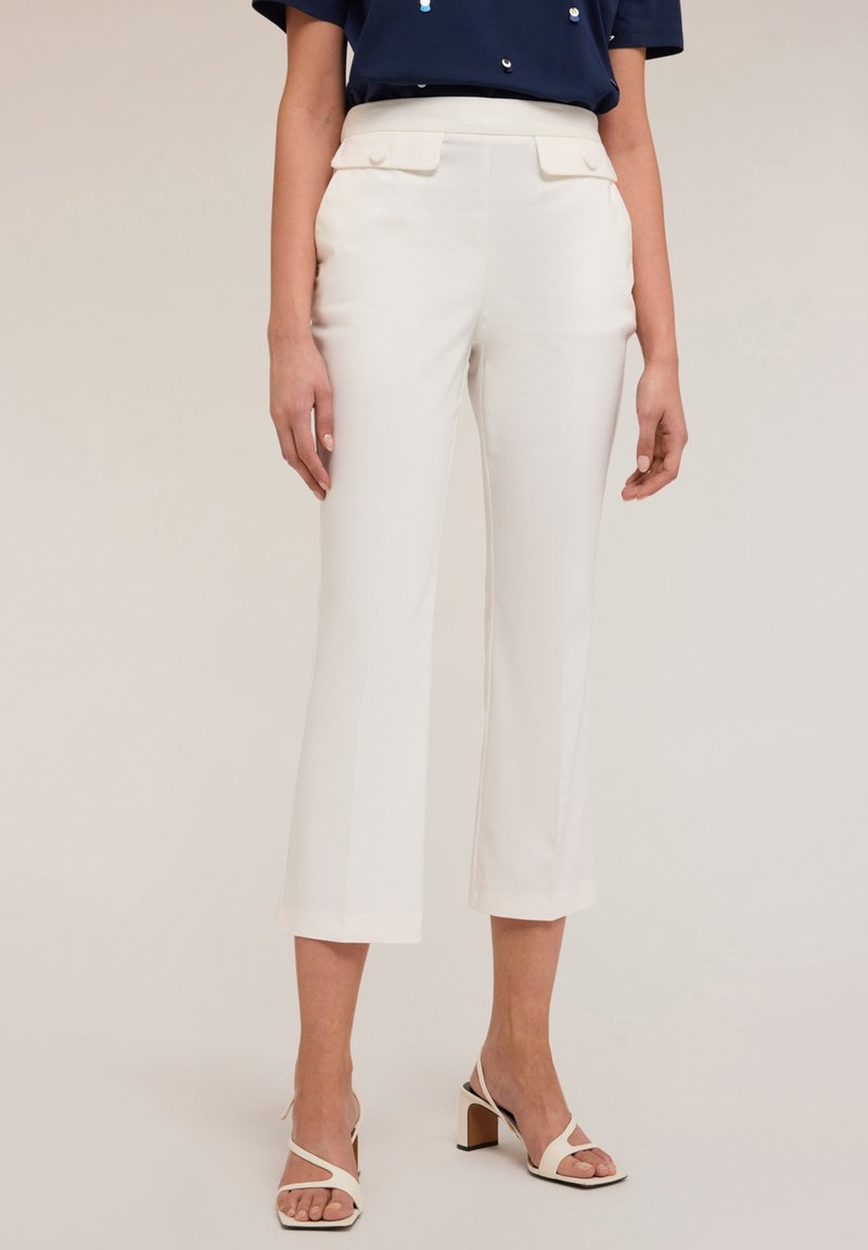 Witte cropped broek met een vlakke voorkant, zijzakken en een gladde textuur, gecombineerd met lichte strappy hakken. Materiaal lijkt op maat gemaakt.