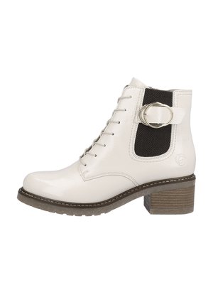 Botte de cheville en cuir blanc avec un bout rond, un laçage à l'avant et une boucle dorée sur un panneau en tissu à chevrons noirs. Talon carré brun.